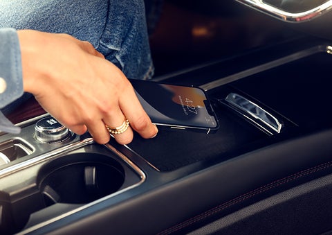 A smartphone is is being placed on the wireless charging pad in the front center console cubby. | Sheehy Lincoln of Gaithersburg in Gaithersburg MD