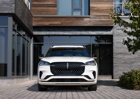 A white 2025 Lincoln Aviator® SUV is shown parked outside a modern building with gray brick and wood accents. | Sheehy Lincoln of Gaithersburg in Gaithersburg MD