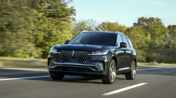 A 2025 Lincoln Black Label Aviator® SUV is being driven down a road lined with trees. | Sheehy Lincoln of Gaithersburg in Gaithersburg MD