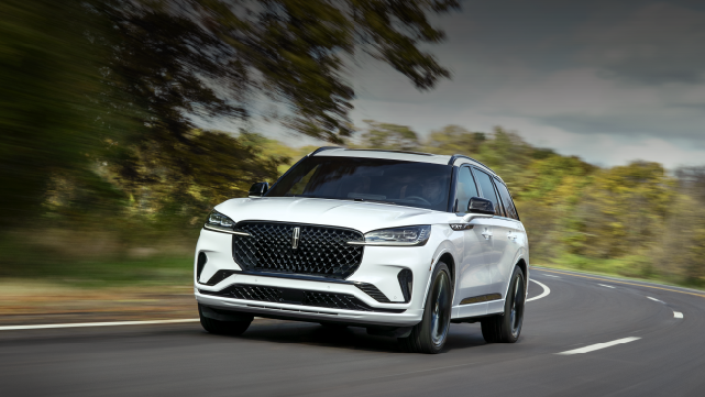 A white 2025 Lincoln Aviator® SUV is being driven down a road lined with trees. | Sheehy Lincoln of Gaithersburg in Gaithersburg MD