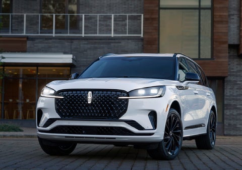 A 2026 Lincoln Aviator® Reserve model is shown with the available Jet Appearance Package parked near a restaurant. | Sheehy Lincoln of Gaithersburg in Gaithersburg MD