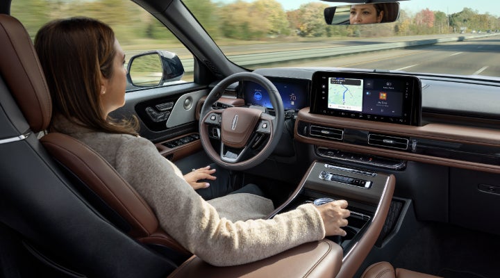 A 2026 Lincoln Aviator® SUV is being driven hands-free on a highway near a forest | Sheehy Lincoln of Gaithersburg in Gaithersburg MD