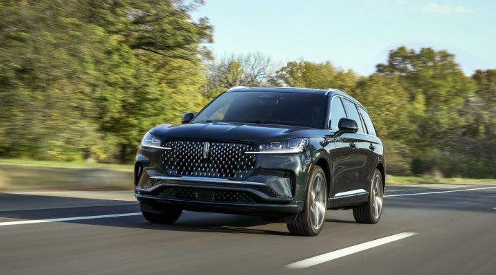 A 2026 Lincoln Black Label™ Aviator® SUV is being driven down a road lined with trees. | Sheehy Lincoln of Gaithersburg in Gaithersburg MD