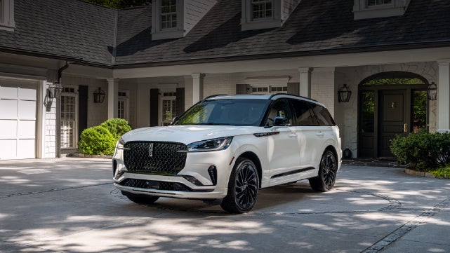 A white 2026 Lincoln Aviator® SUV is parked in the driveway of a luxury home. | Sheehy Lincoln of Gaithersburg in Gaithersburg MD