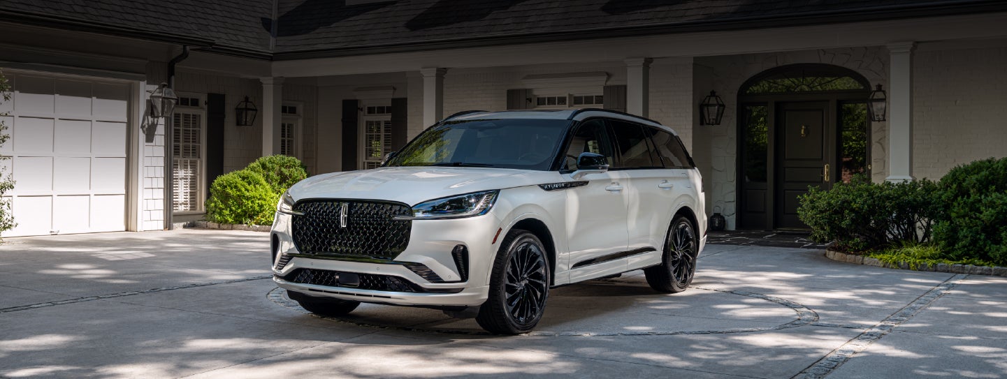 A white 2026 Lincoln Aviator® SUV is parked in the driveway of a luxury home. | Sheehy Lincoln of Gaithersburg in Gaithersburg MD