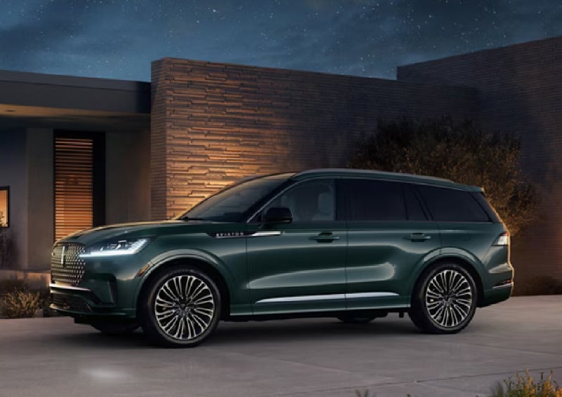 A green 2027 Lincoln Aviator® SUV is parked outside a contemporary home. | Sheehy Lincoln of Gaithersburg in Gaithersburg MD
