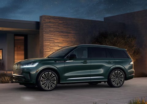 A green 2027 Lincoln Aviator® SUV is parked outside a contemporary home. | Sheehy Lincoln of Gaithersburg in Gaithersburg MD