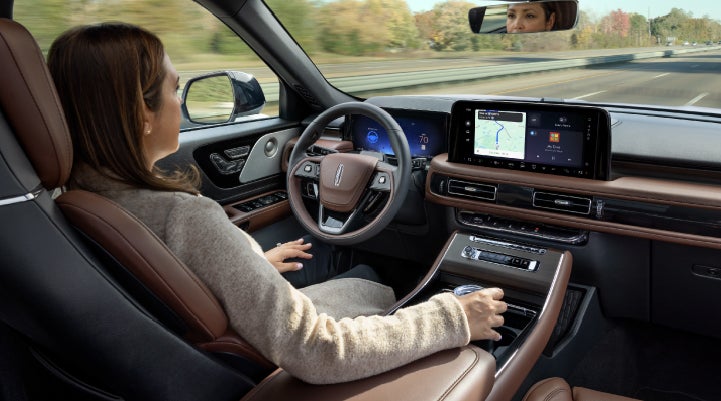 A 2027 Lincoln Aviator® SUV is being driven hands-free on a highway lined with trees. | Sheehy Lincoln of Gaithersburg in Gaithersburg MD